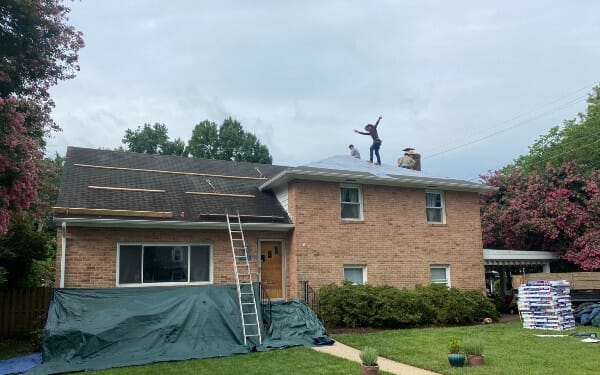K&J employees working on roof repair of brick home